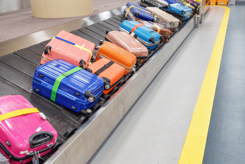 photo of Bright colorful suitcases and bags on luggage conveyor belt at arrival area of passenger terminal in airport. Baggage carousel.
