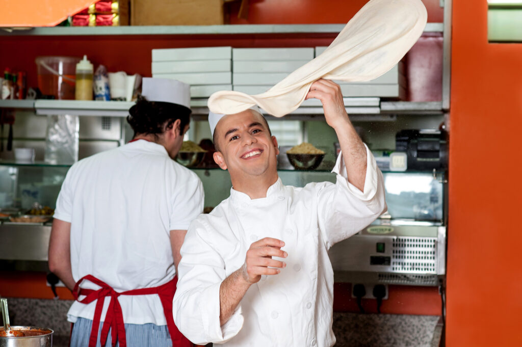 photo of Skilled chef throwing up pizza base dough