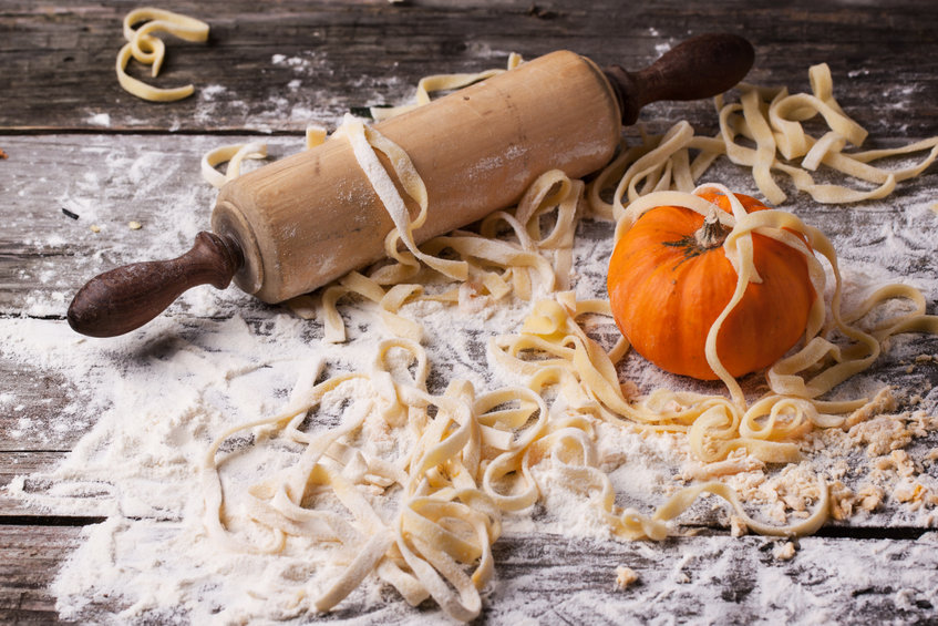 photo of Raw homemade pasta with pumpkin, flour and vintage rolling pin over old wooden table